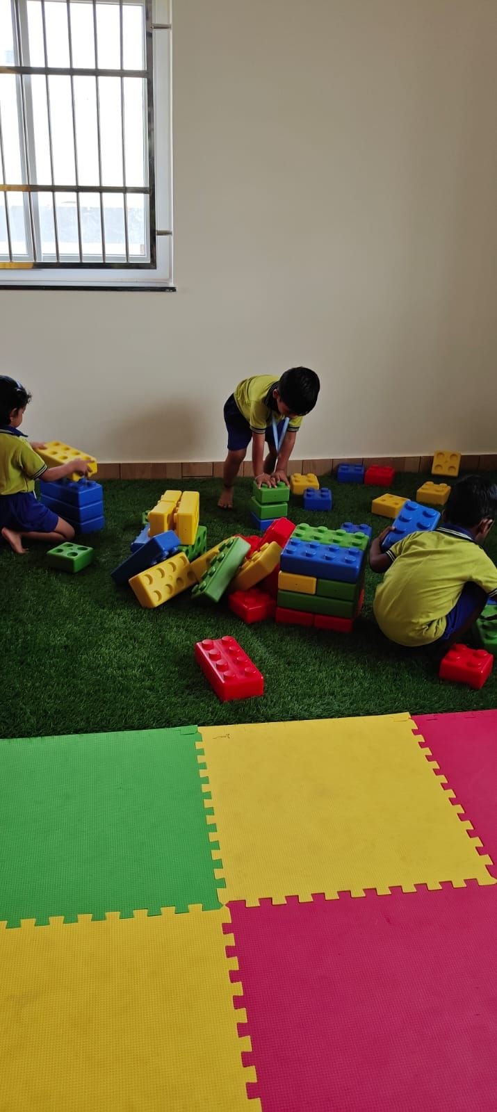 Children building with giant blocks on the play turf