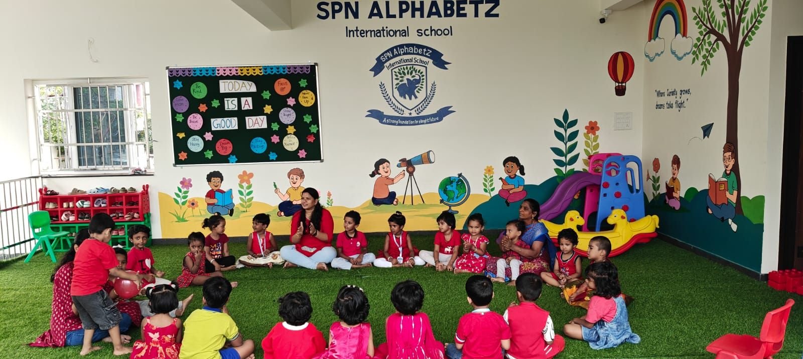 Circle time with teachers under the SPN AlphabetZ mural wall