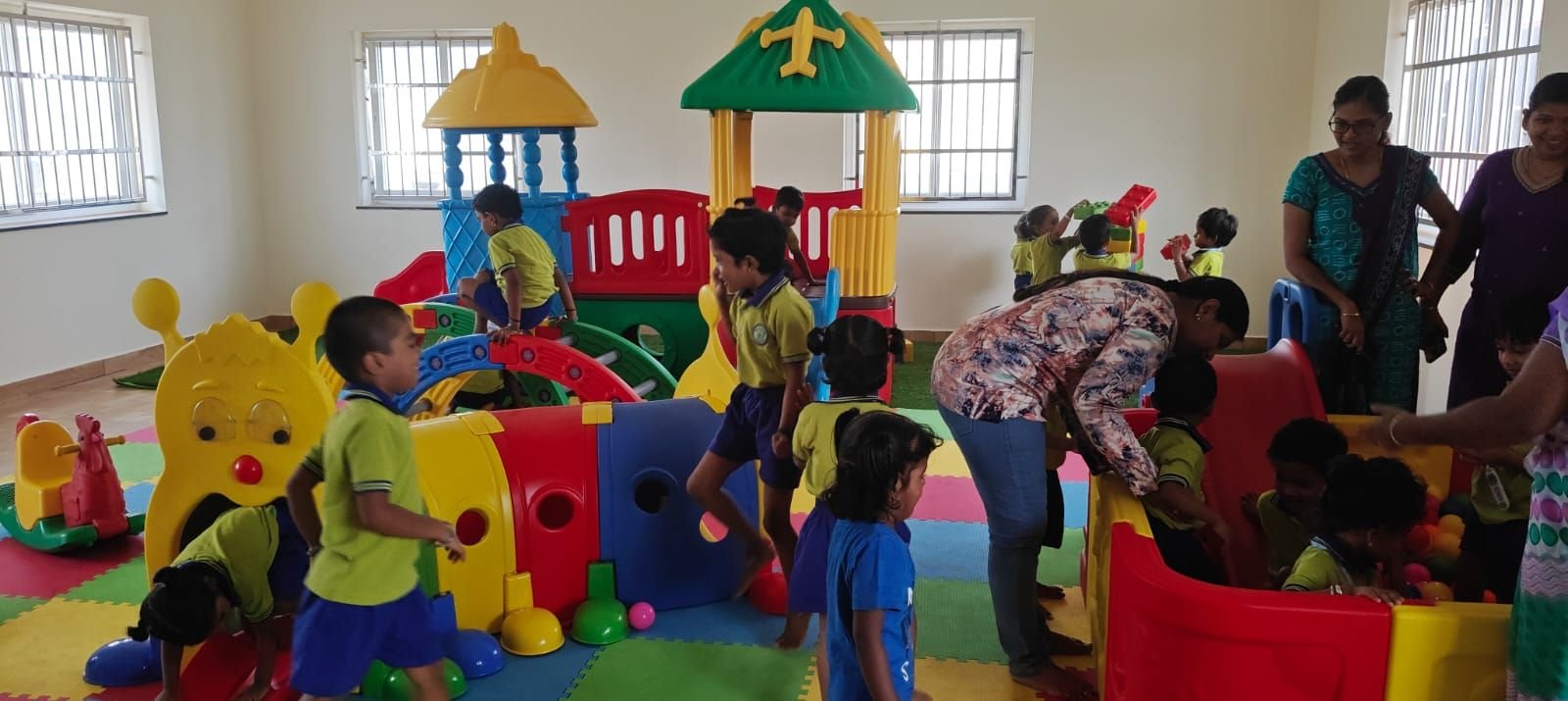 Teachers guiding children on the play structure